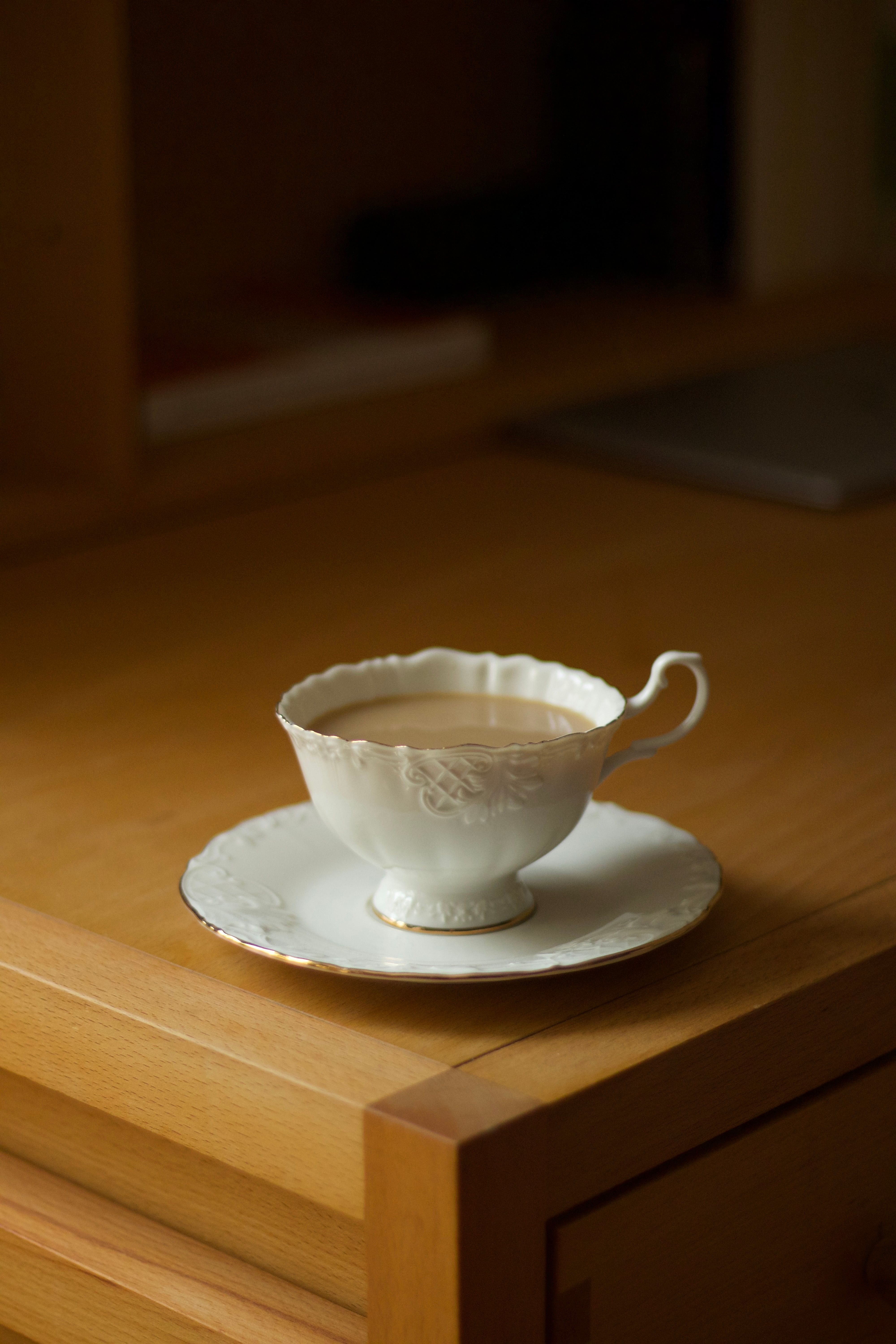 Charming vintage porcelain teacup filled with tea on a wooden table, evokes warmth and tranquility.