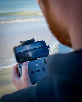 Person using a drone controller by the sea at St. Pete Beach, Florida.