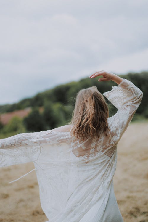 Woman Walking on a Meadow with Arms Spread 