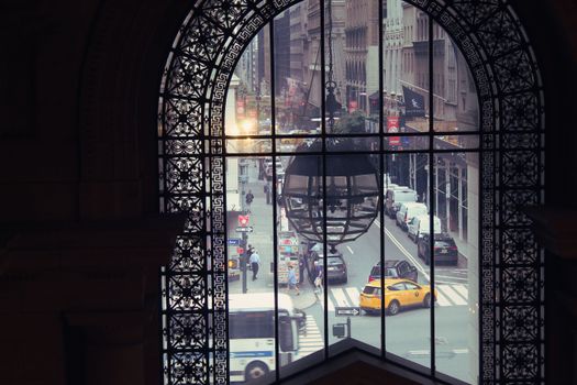 A bustling New York City street scene as viewed through a decorative window, capturing the urban hustle.