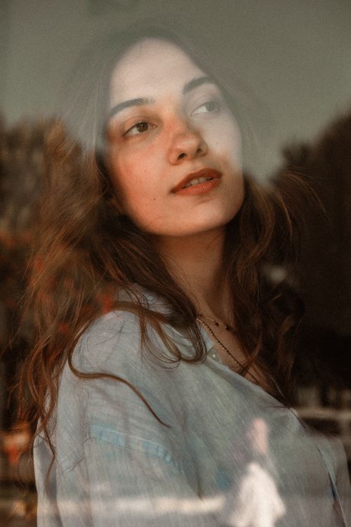 Free Elegant portrait of a woman looking through a window, capturing a serene and reflective mood. Stock Photo