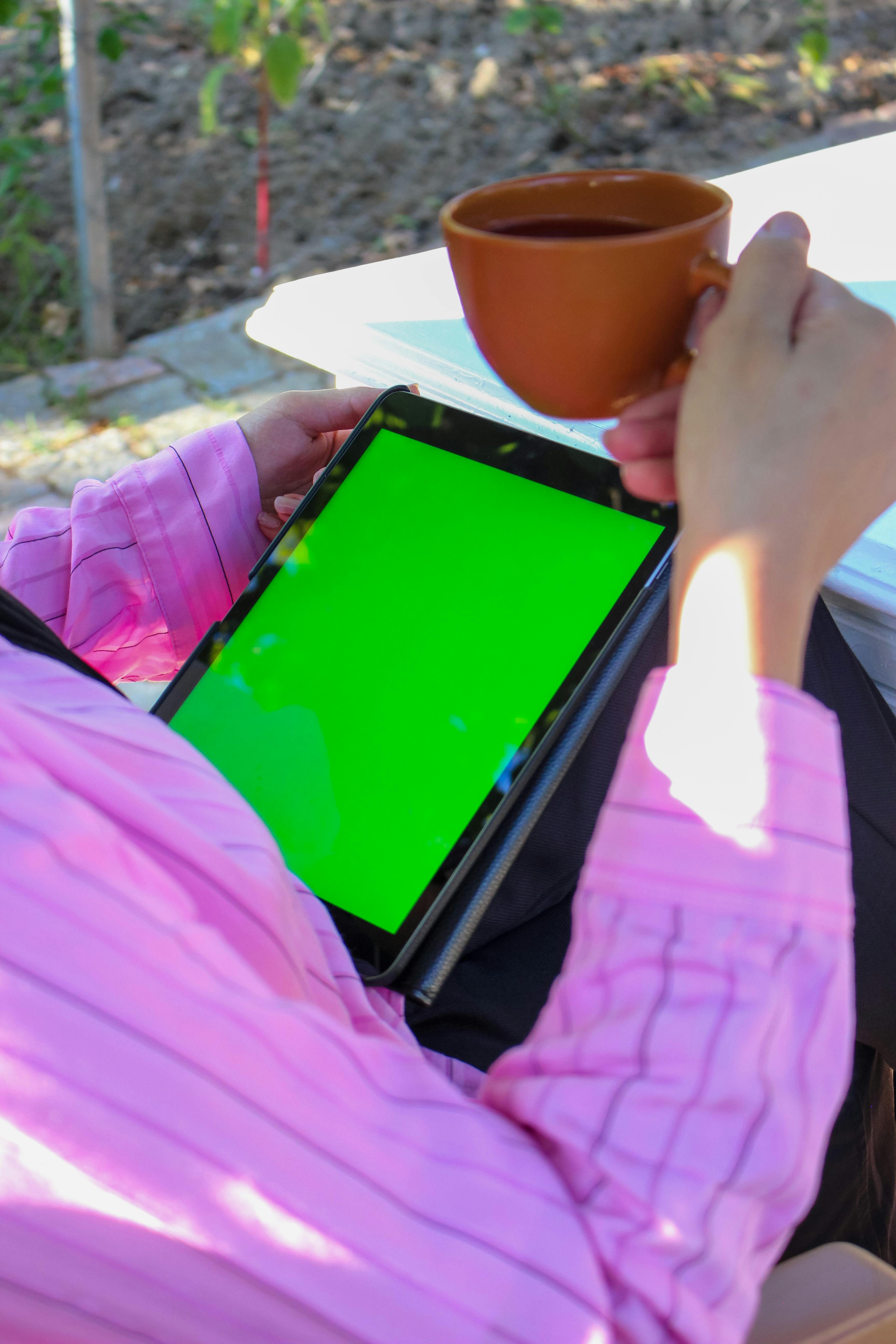 a woman drinking coffee and using a tablet