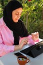 A Woman in a Hijab Working on a Tablet