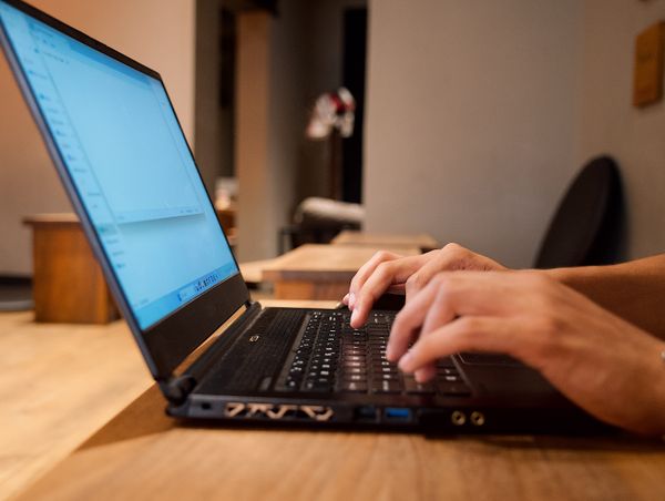 Hands typing on a laptop in a modern office