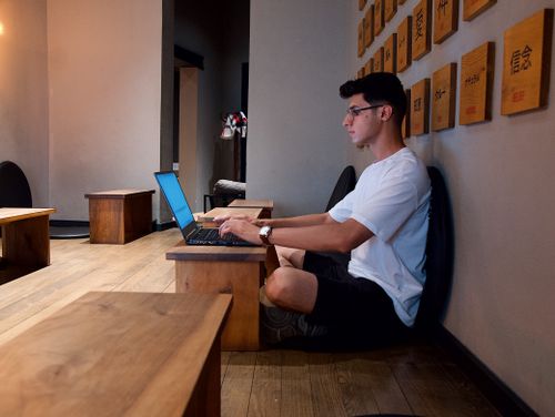 Free A young adult working remotely on a laptop indoors, representing modern digital nomad lifestyle. Stock Photo