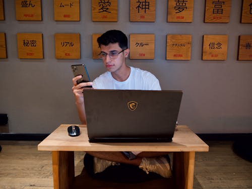 A Man Sitting with a Laptop and a Smartphone