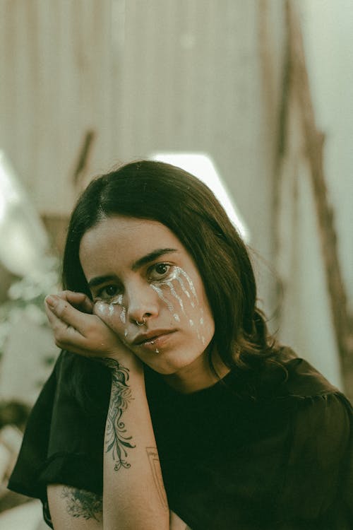 Photo of a Young Woman with Tattoos Wearing Artistic Makeup 