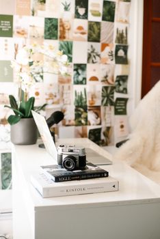 A stylish desk setup with books, a vintage camera, and decorative elements in a modern room.
