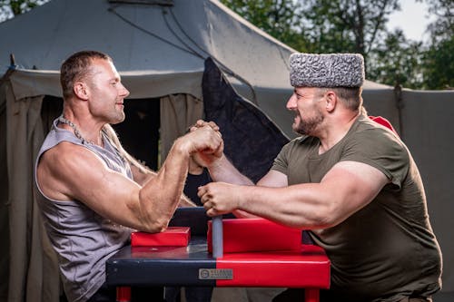 Muscular Men Arm Wrestling Near Tent