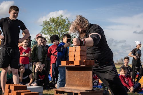 Children Watching Man Breaking Bricks During Strongman Competition