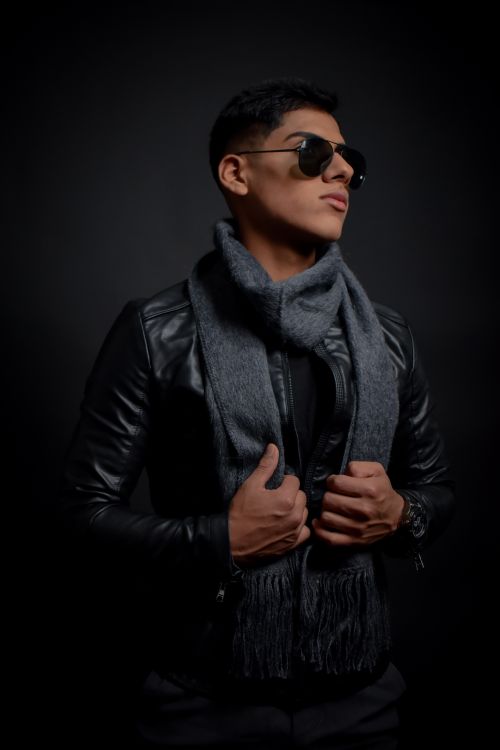Free Portrait of a fashion-forward man in a leather jacket and scarf, exuding confidence. Stock Photo