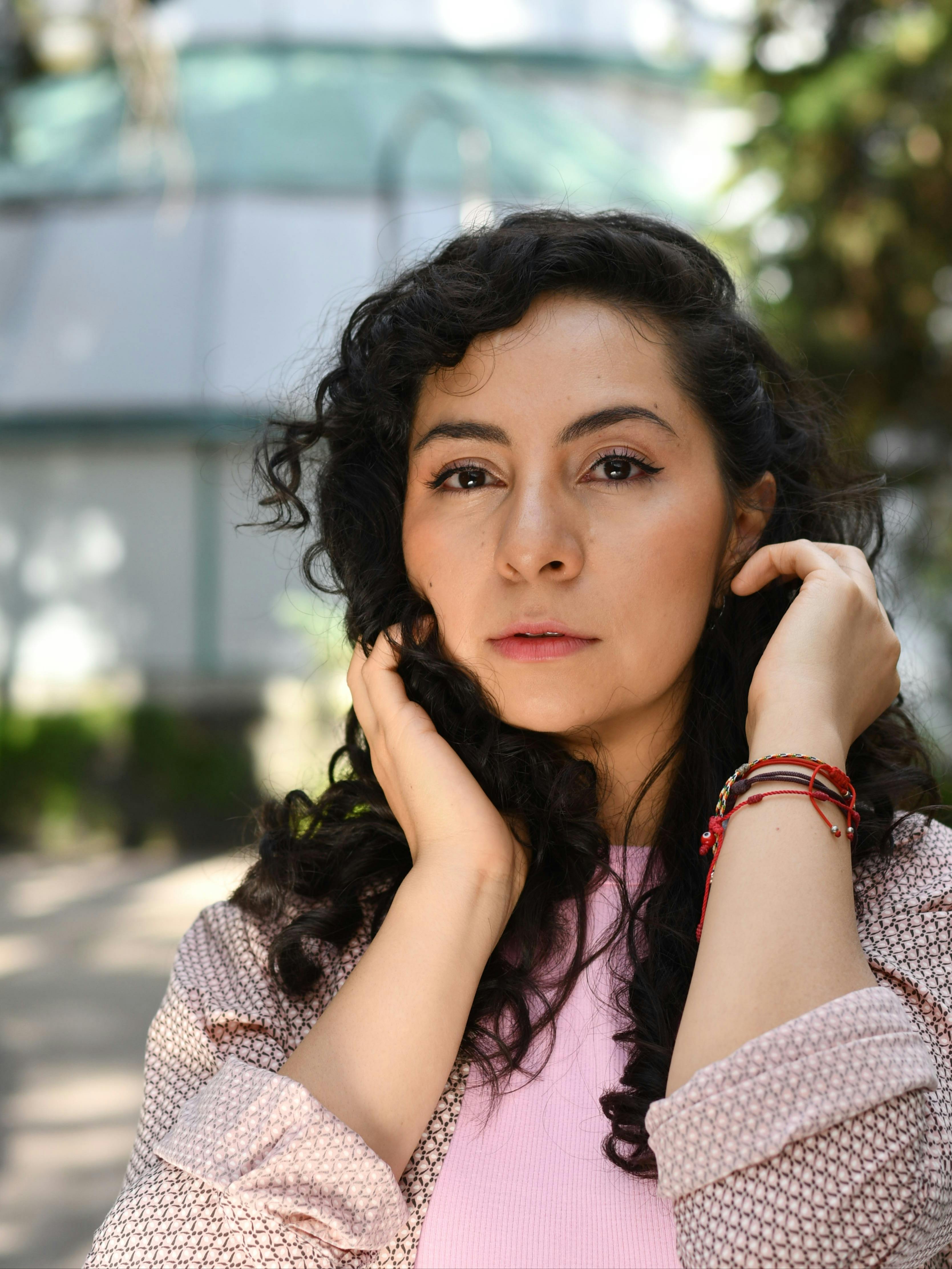 A woman with curly hair poses gracefully outdoors in Ciudad de México.