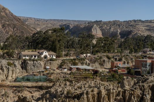 Sunlit La Paz village with dramatic eroded rock formations and lush trees.
