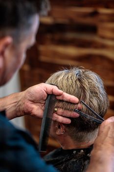 Close-up of a hairstylist cutting hair with scissors in a modern salon.