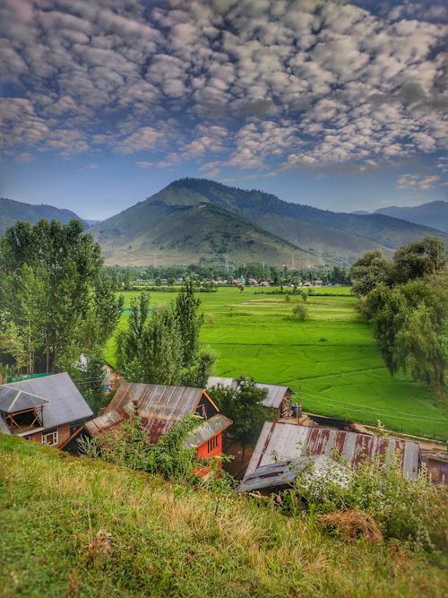 Mountain Landscape with Green Fields and Rusted Roofs