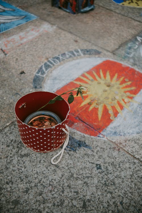 Sun Painted and a Bucket with Coins on a Pavement