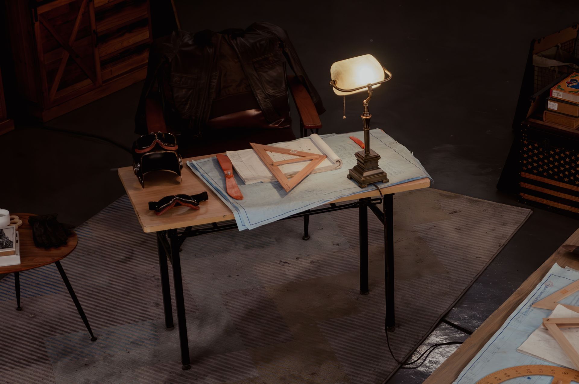 A moody workshop desk with a brass lamp, drafting tools and leather, in warm brown tones