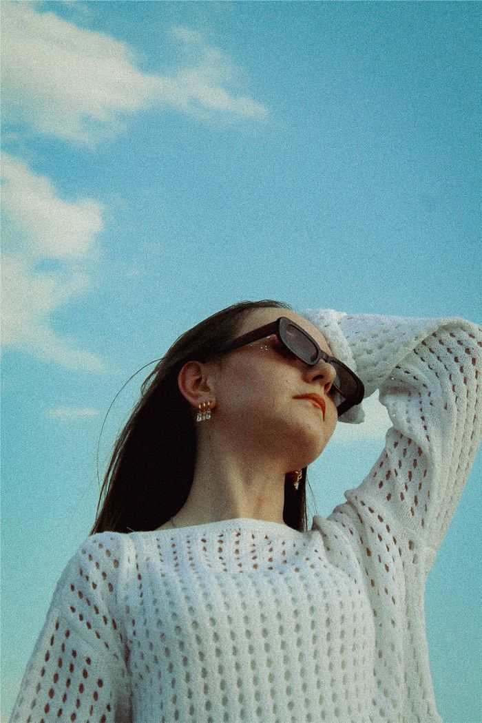Low-angle portrait of a woman in sunglasses against a clear sky — photo by Seher Doğan on Pexels
