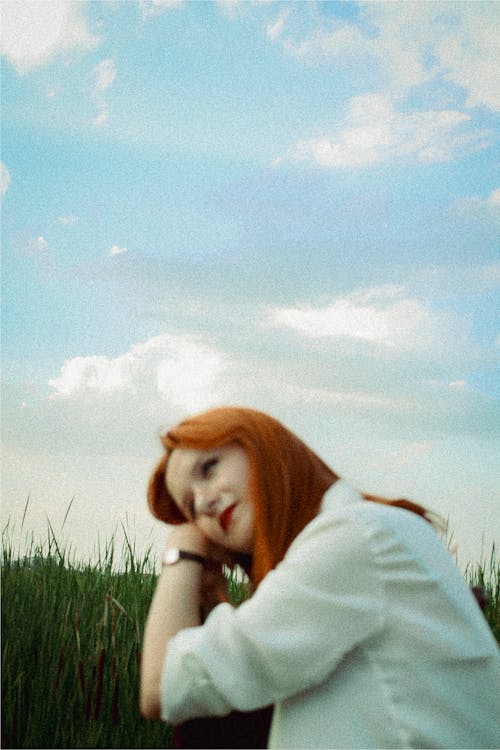 Young Redhead Sitting on a Grass Field 