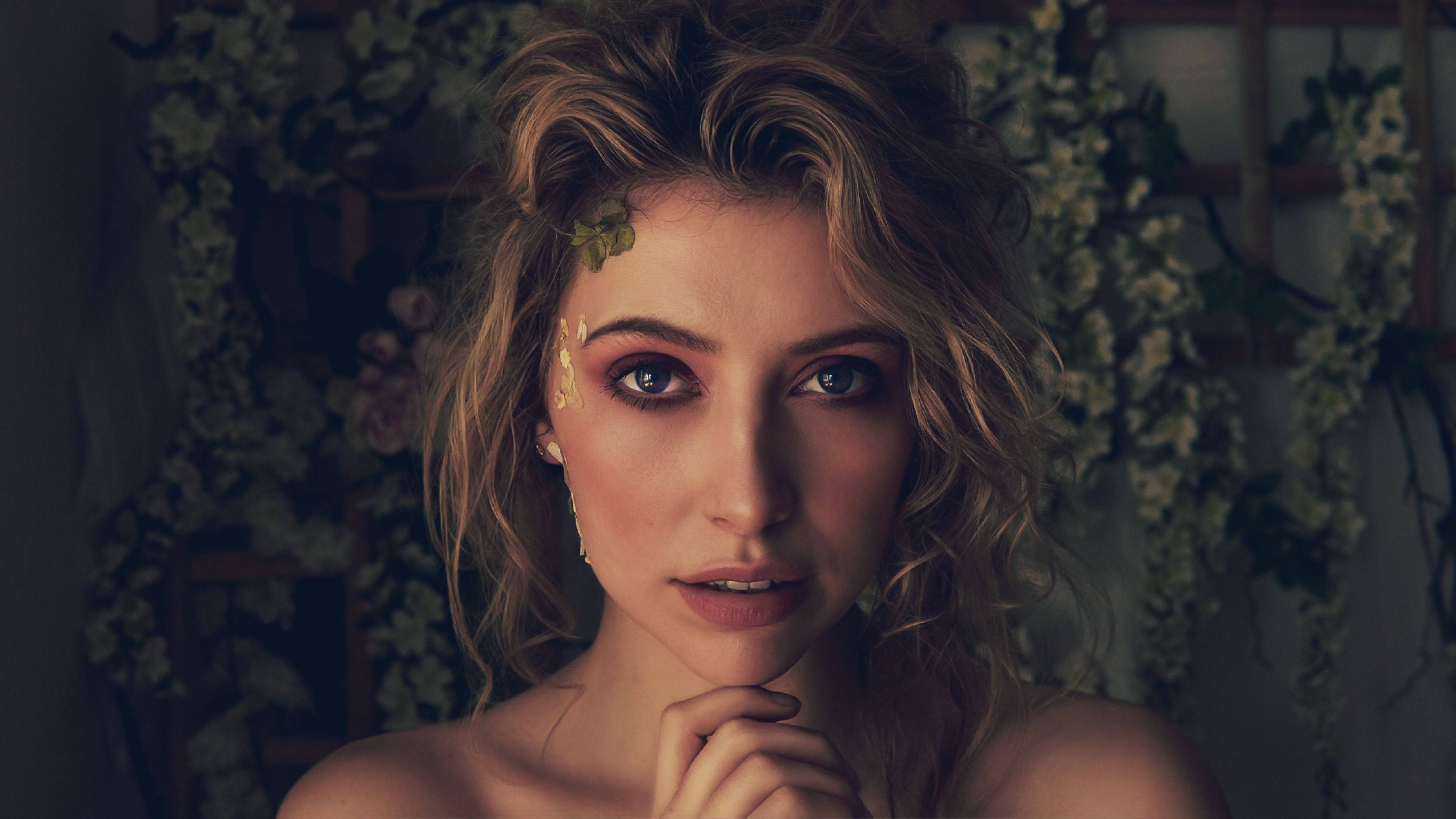 Elegant portrait of a woman in London with a floral backdrop, showcasing natural beauty.