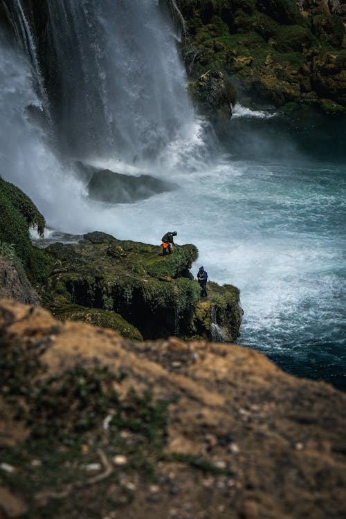 People on Rocks by the Waterfall 