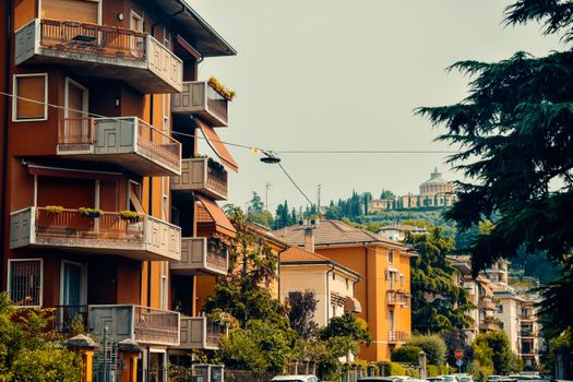 Explore the vibrant architecture of a sunny street in Verona, surrounded by lush greenery and distinctive Italian buildings.