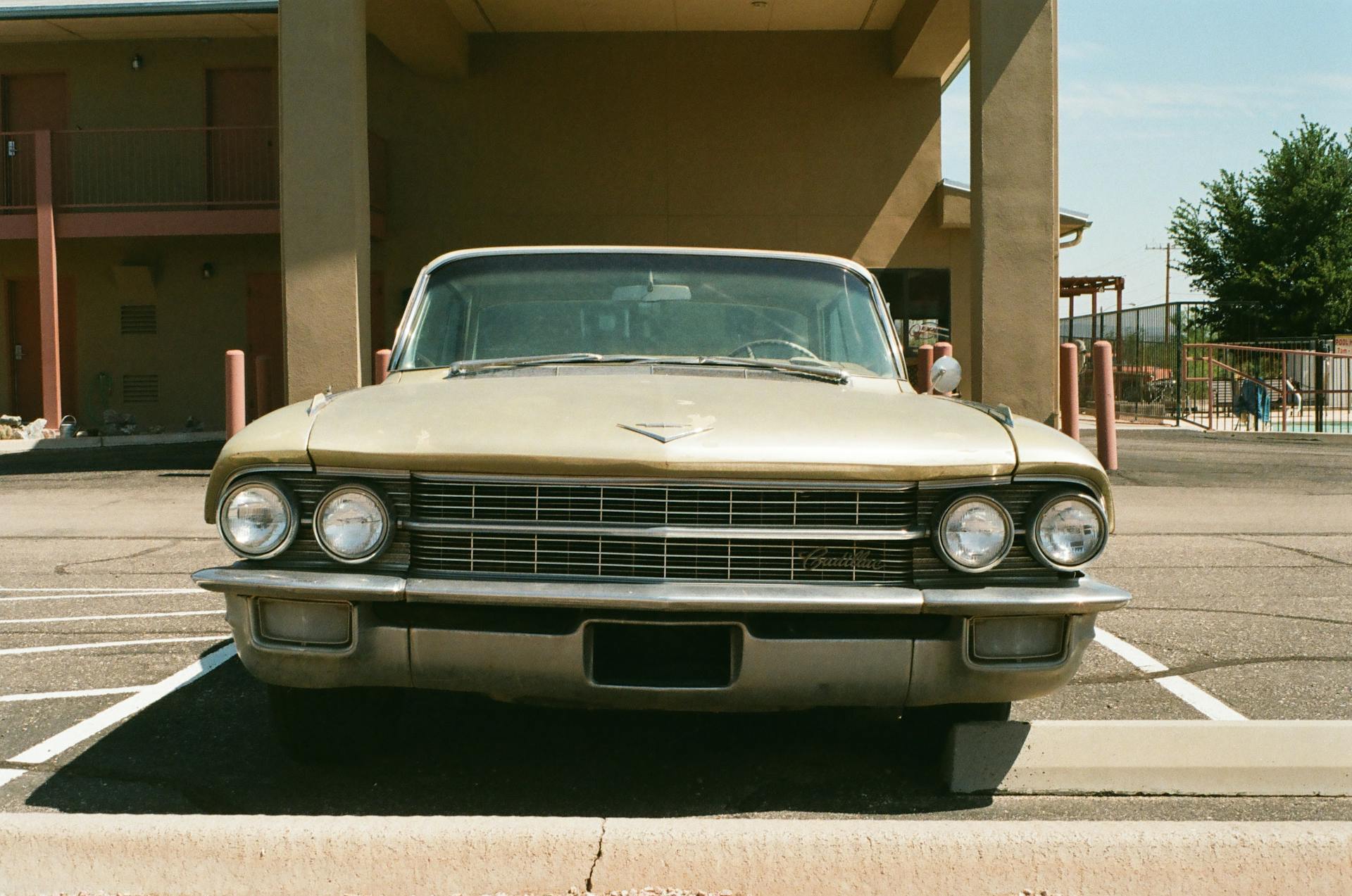 Front view of a classic Cadillac parked in an outdoor lot, evoking retro vibes.