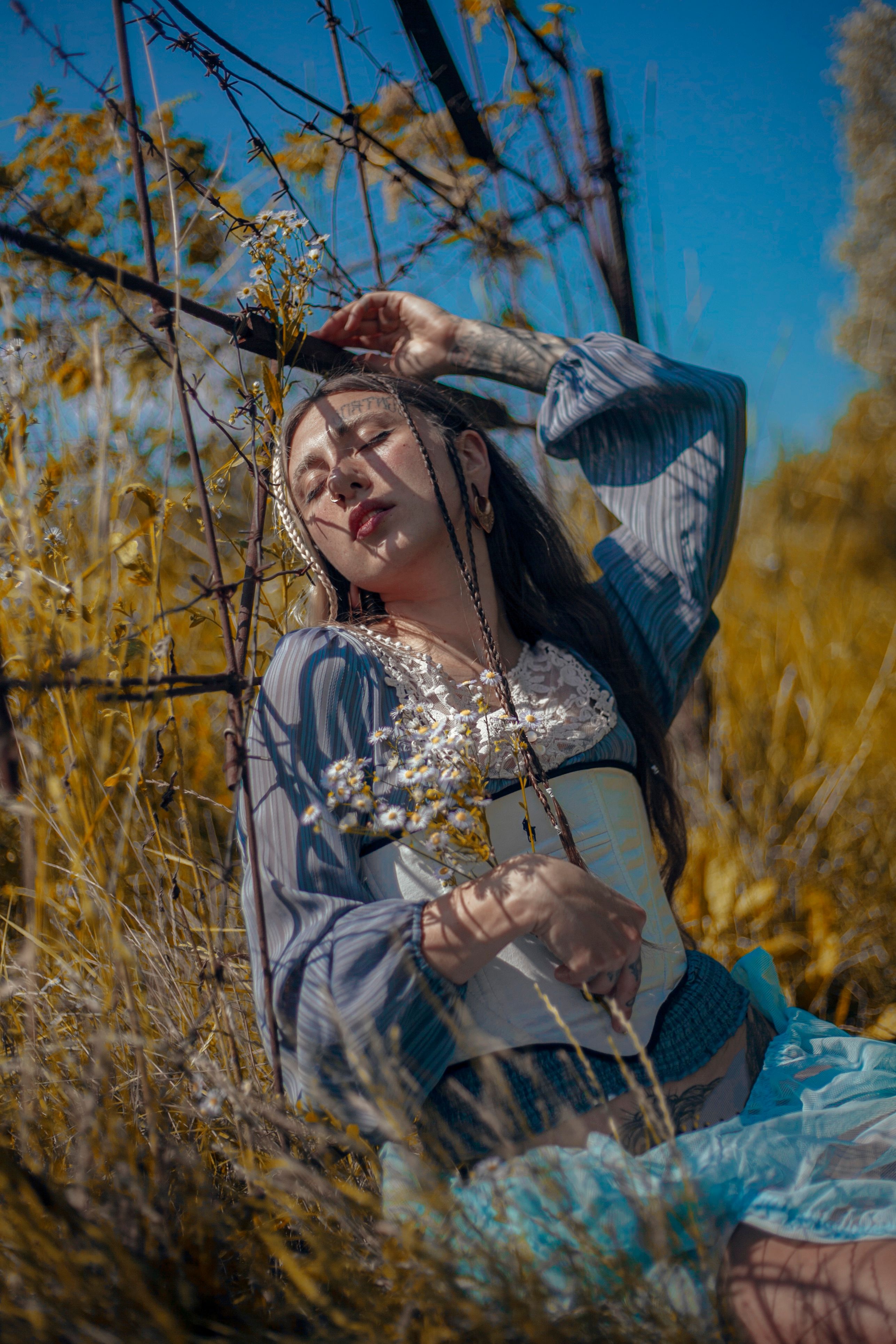 Young Woman Sitting on a Rural Field with Eyes Closed · Free Stock Photo