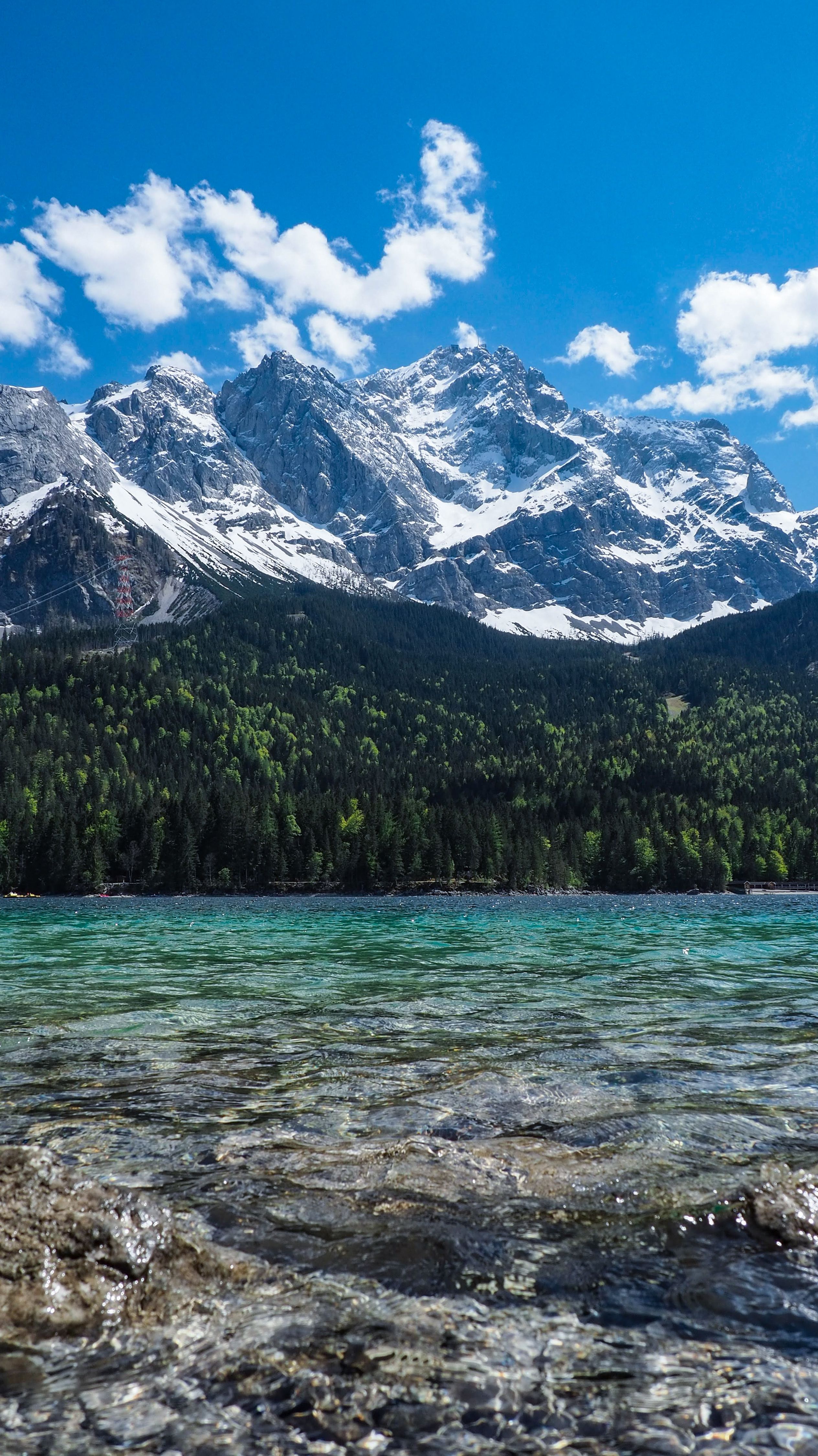 Stunning view of a snow-capped mountain range above a pristine turquoise lake under blue skies.
