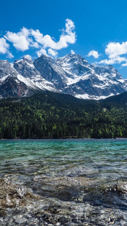 Free Stunning view of a snow-capped mountain range above a pristine turquoise lake under blue skies. Stock Photo