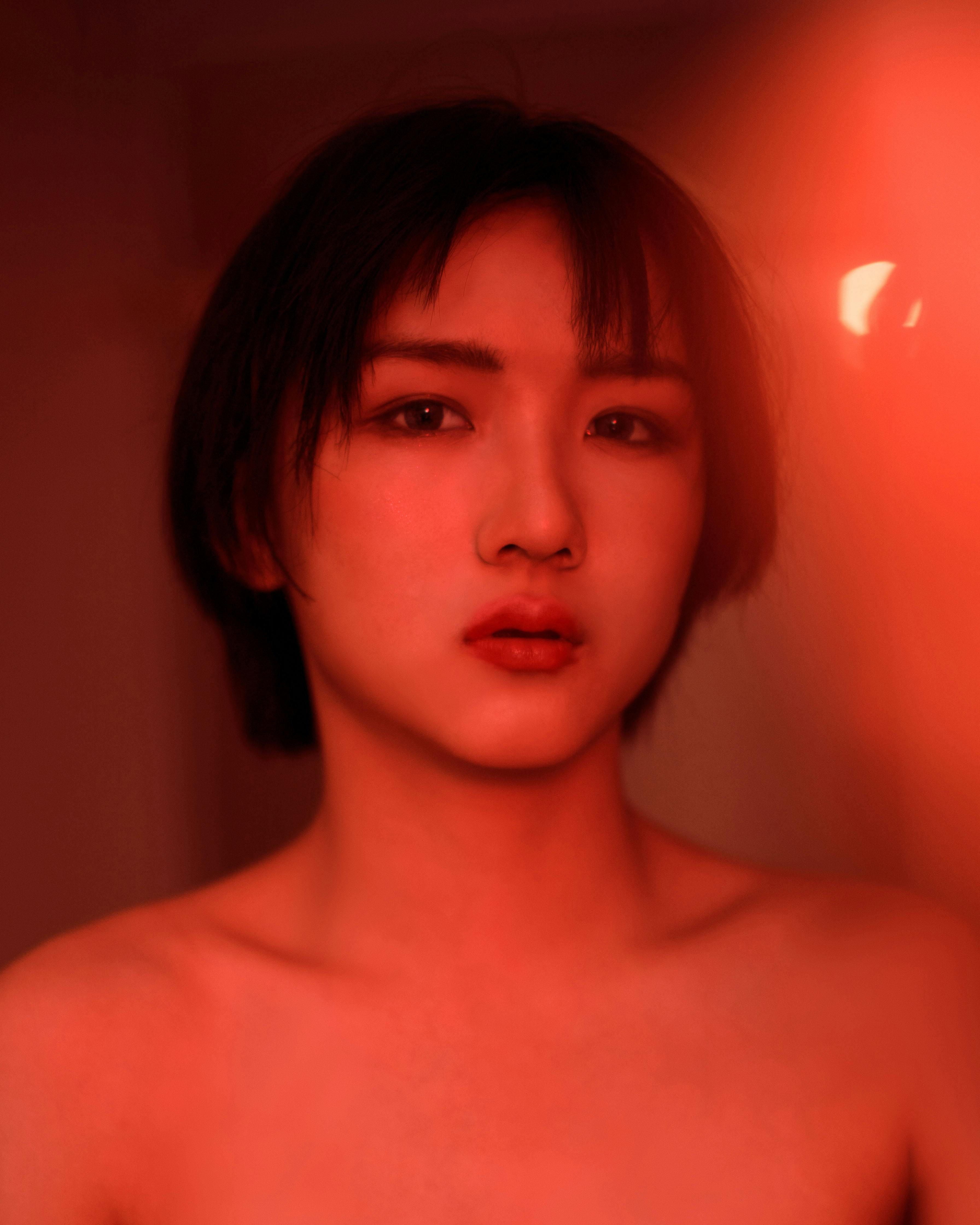 Captivating portrait of a young woman illuminated by dramatic red lighting, creating an intense atmosphere.
