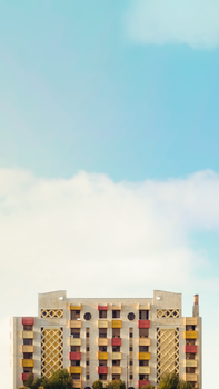 Symmetrical apartment building with colorful balconies against a bright sky.