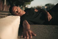 白天，一个男人以休闲的姿势在人行道上休息