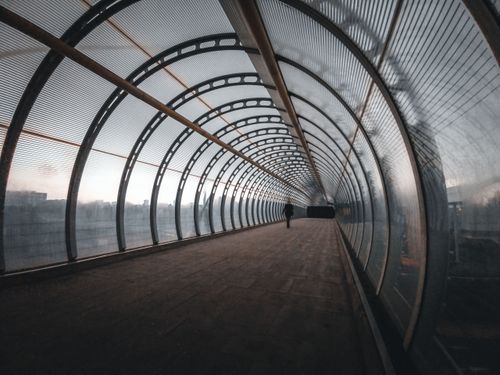 Free A sleek, curved pedestrian tunnel in Canary Wharf, London, with a silhouette walking inside. Stock Photo