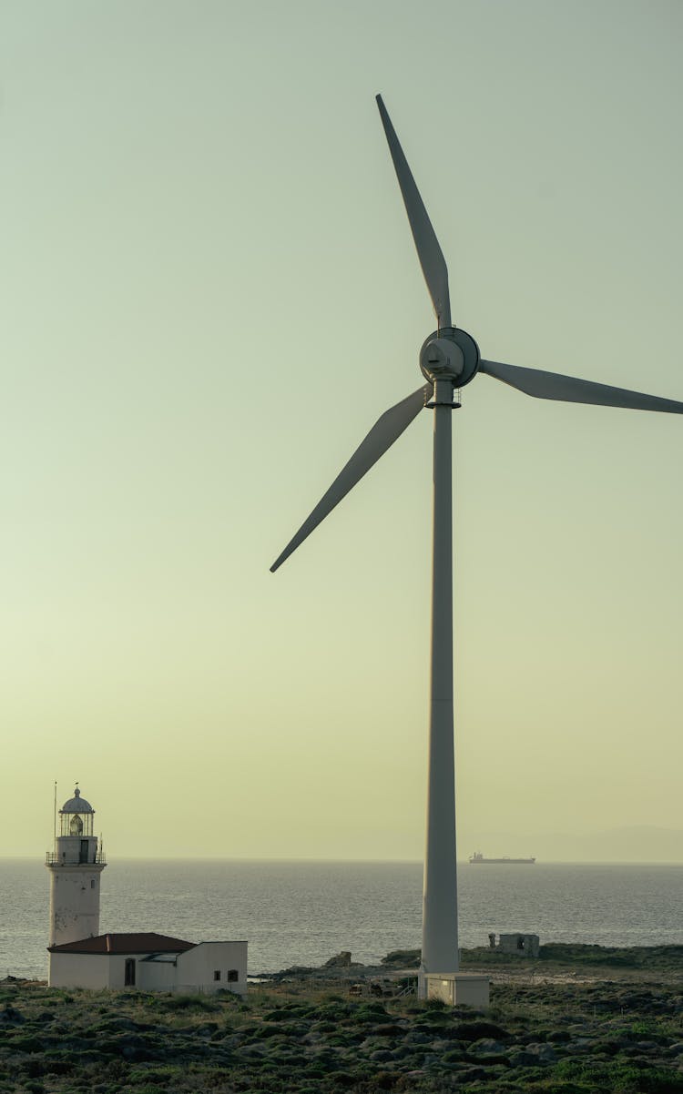 Wind Turbine And Lighthouse By Sea