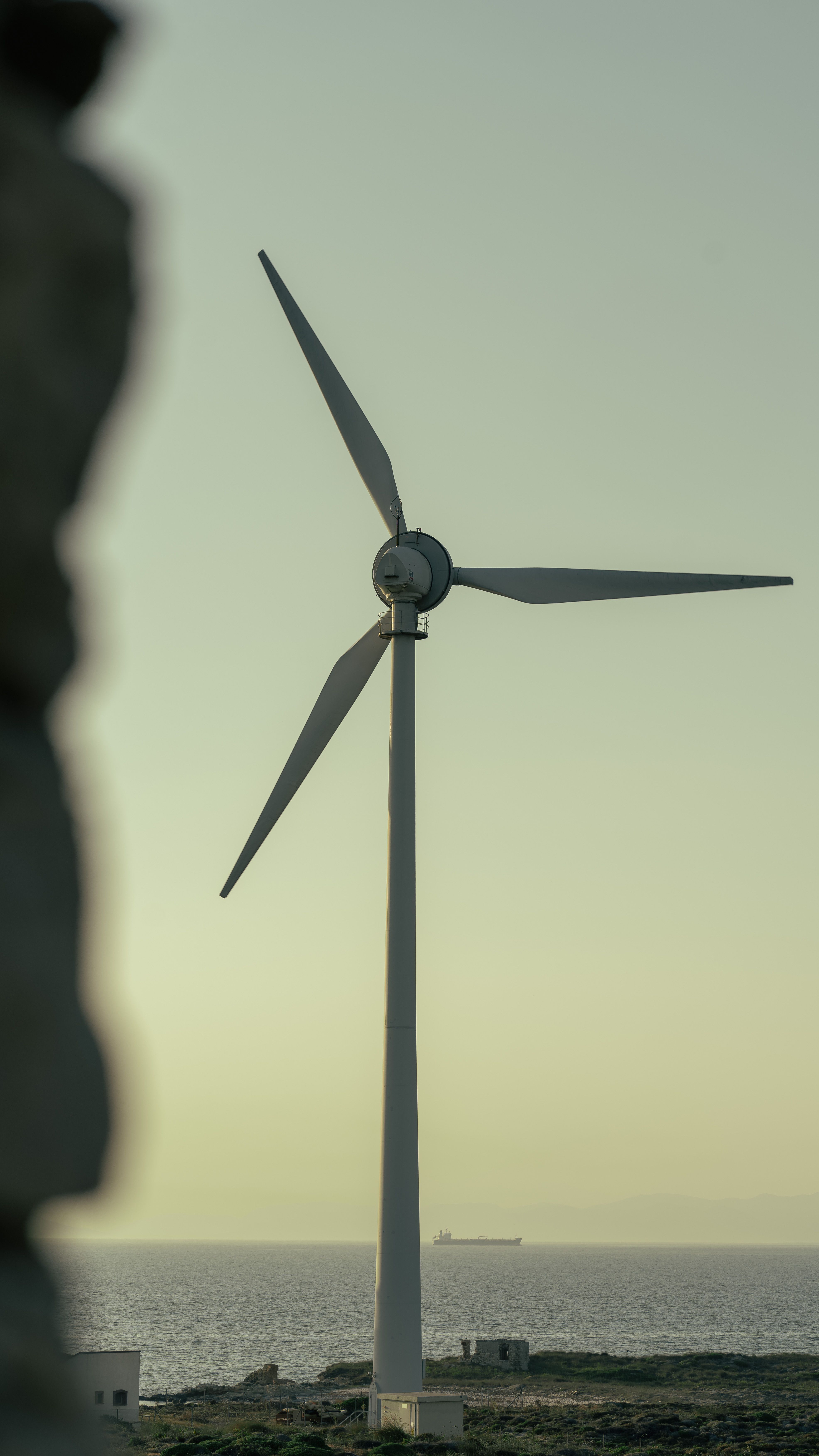 Fotomural Turbina eólica en la isla de Bozcaada, promoviendo energía renovable contra el sereno fondo del Mar Egeo.
