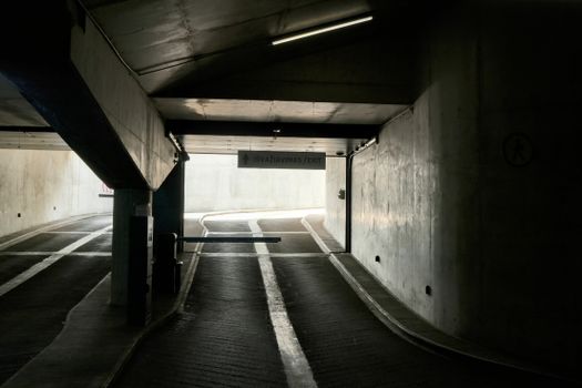 Dark urban underground parking exit in Kaunas, Lithuania with shadows and concrete walls.