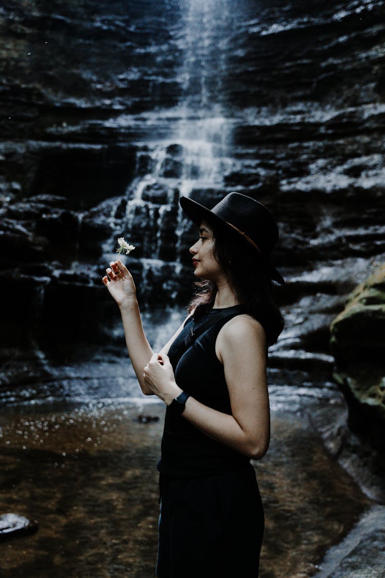 Woman Holding Flower By Waterfall