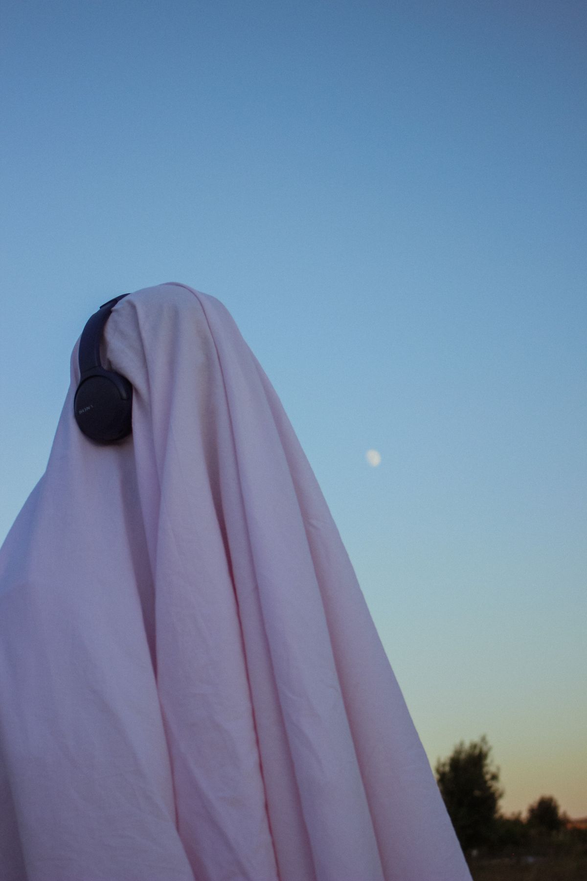 A playful Halloween ghost costume wearing headphones.