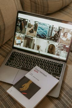 A cozy workspace with a laptop open on a couch and a book titled 'Knut Hamsun'.