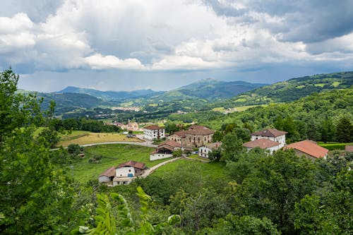 Landscape of Houses in a Valley and Mountains Covered in Green Trees 