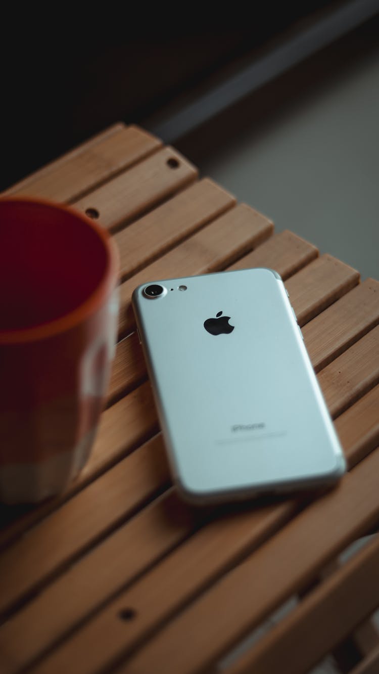 Close-up Of An IPhone Lying On A Table Next To A Cup 