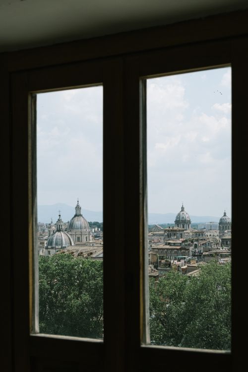 Free Stunning view of Rome's historical cityscape featuring iconic domes through a window frame. Stock Photo