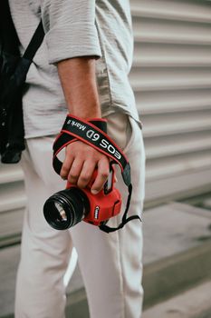 Close-up of a man holding a camera in a red protective cover outdoors.