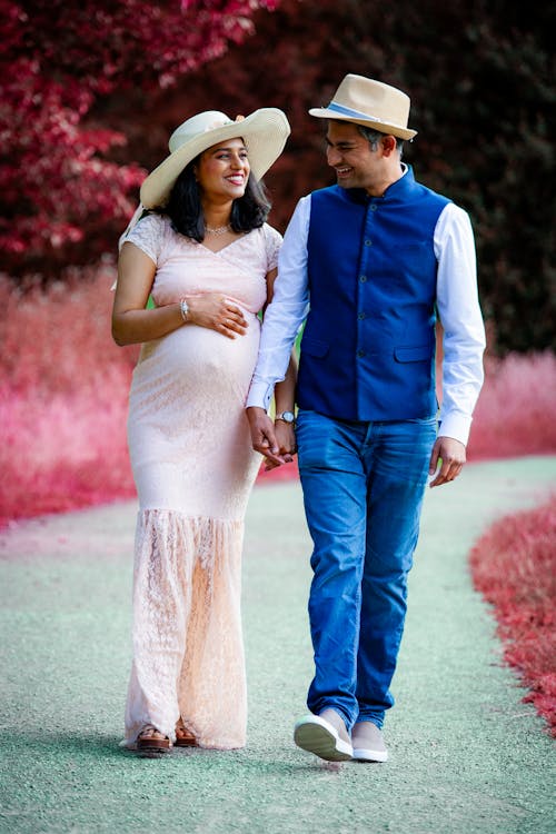 A Pregnant Woman and Her Partner Walking Together and Smiling 