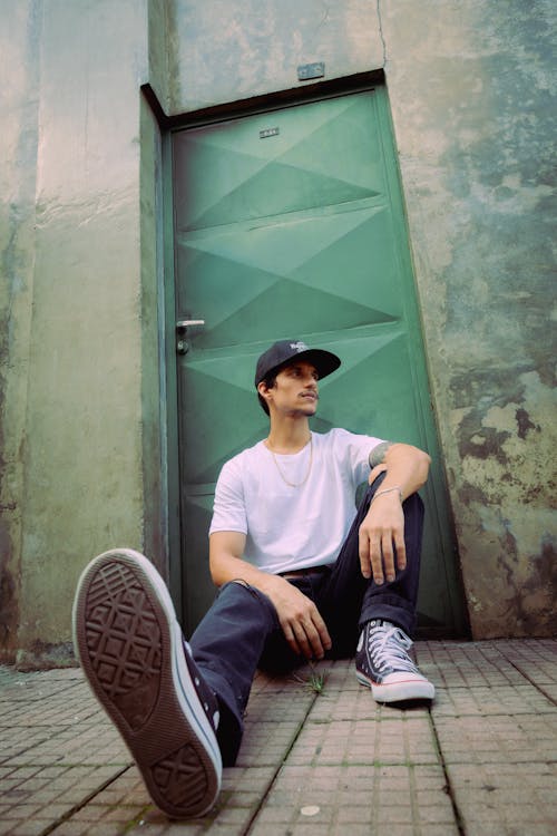 Man in Cap and T-shirt Sitting by Door