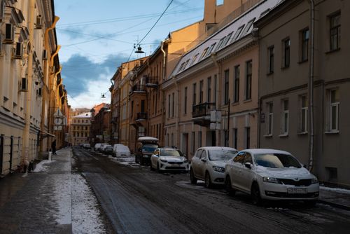 Free A serene urban street covered in snow with parked cars during winter. Stock Photo