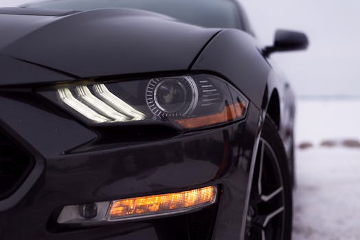 Detailed view of a modern car headlight with snow in the background, highlighting design and winter season.