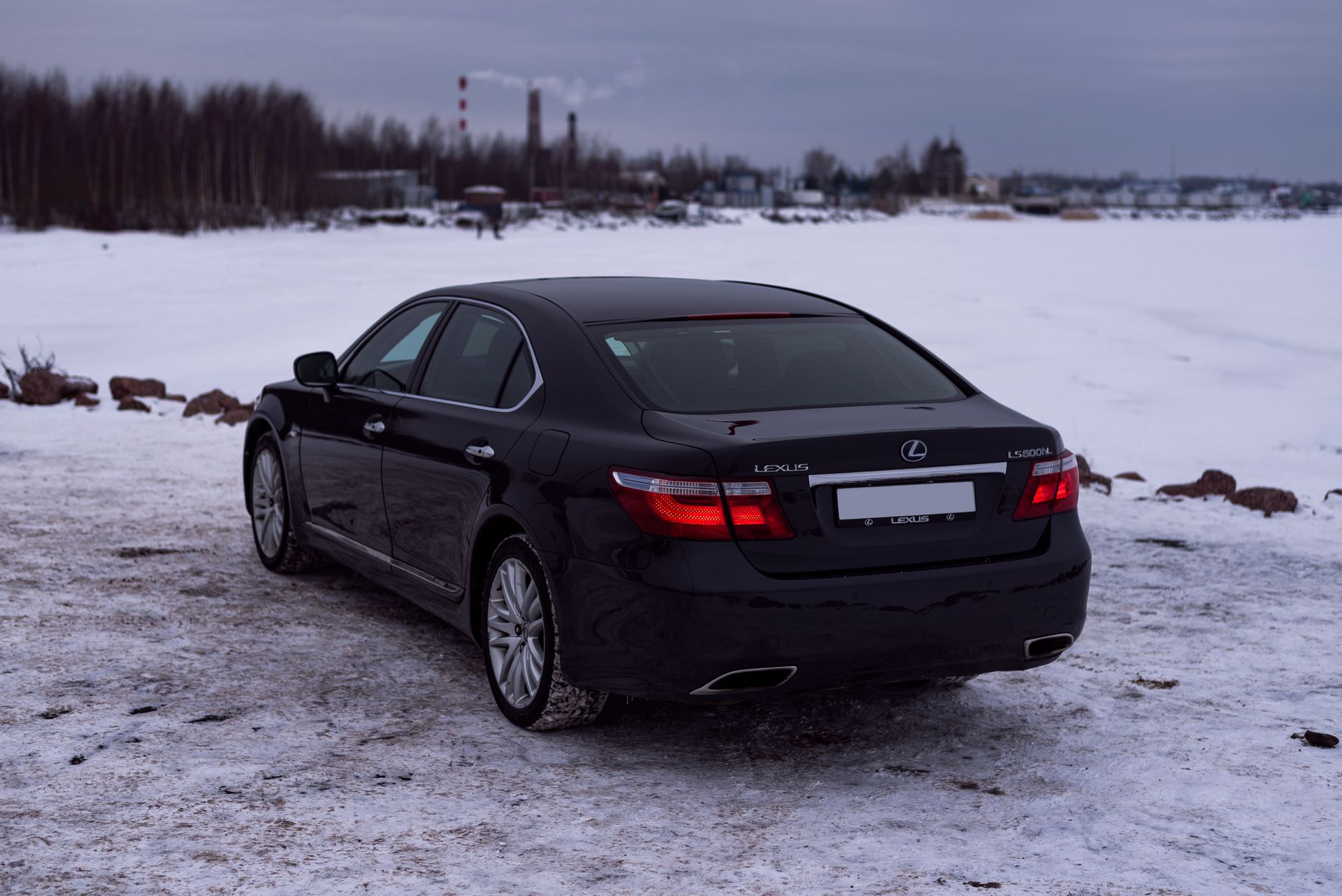 A sleek black Lexus LS 460 parked on a snowy field during winter, showcasing modern automotive design.