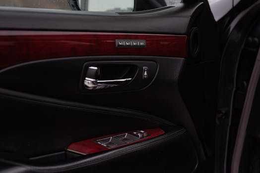 Close-up of a luxury car door featuring chrome handles and wooden panel detailing.